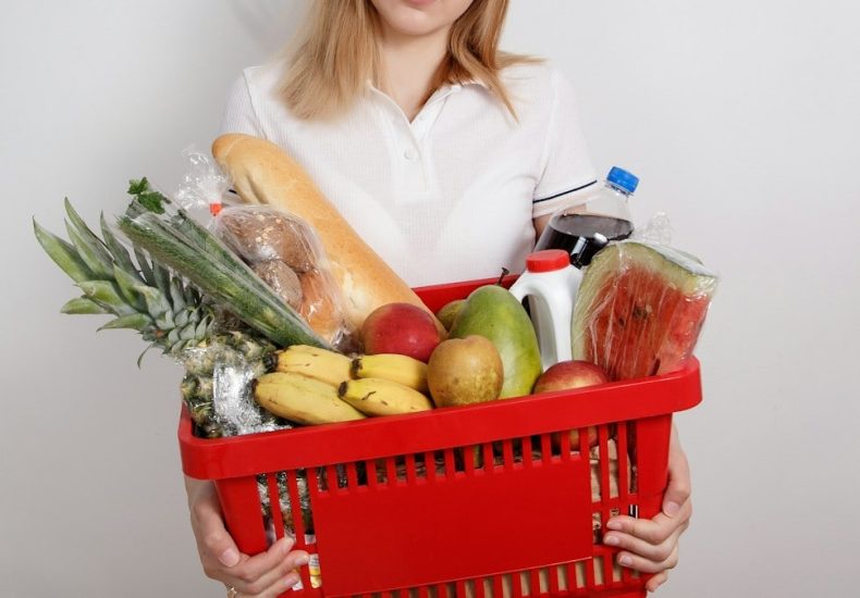 Young woman with goods in basket. The girl made a purchase. Girl holding a basket of groceries. Vegetables
